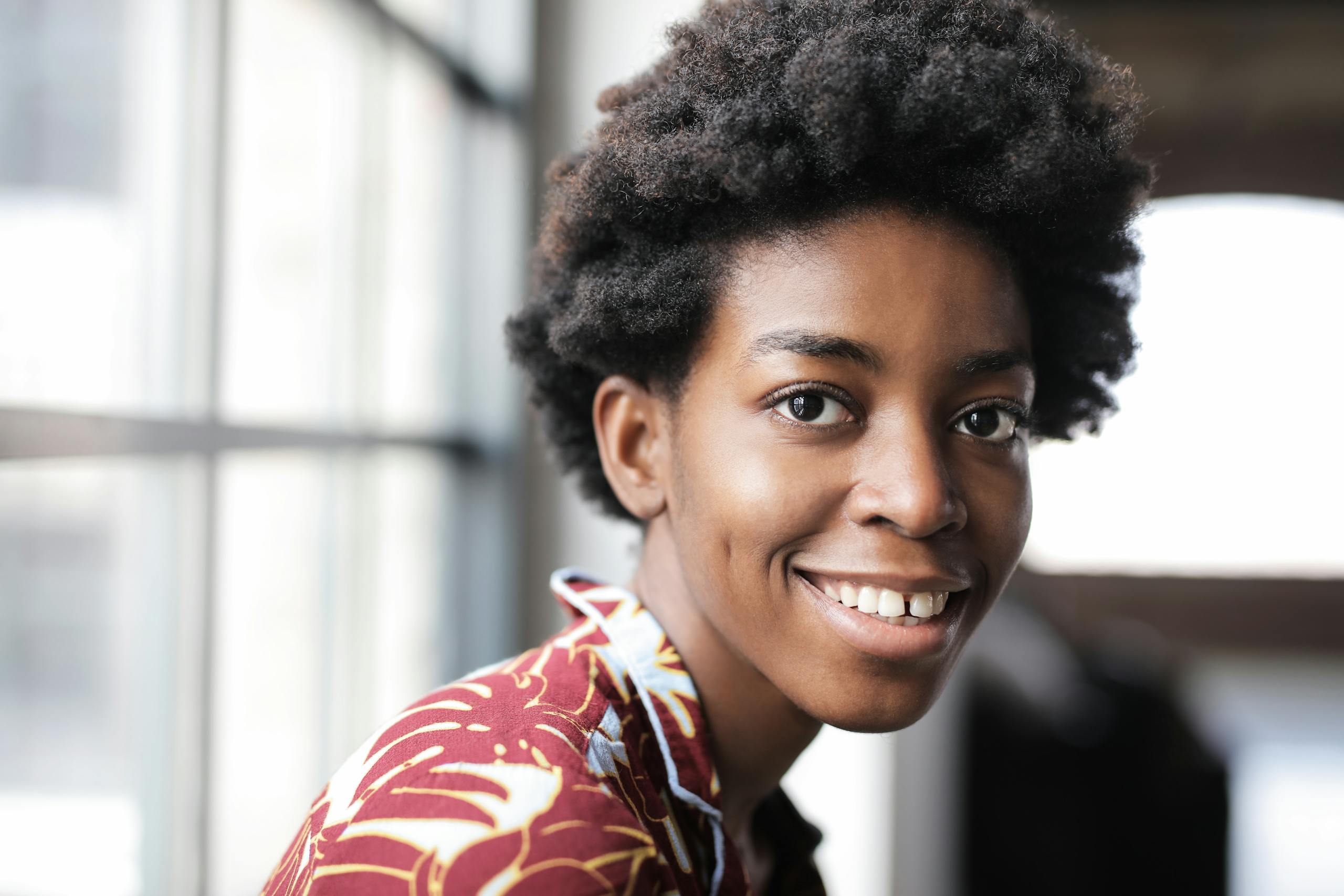 Close-up of a joyful Black woman with curly hair smiling indoors.